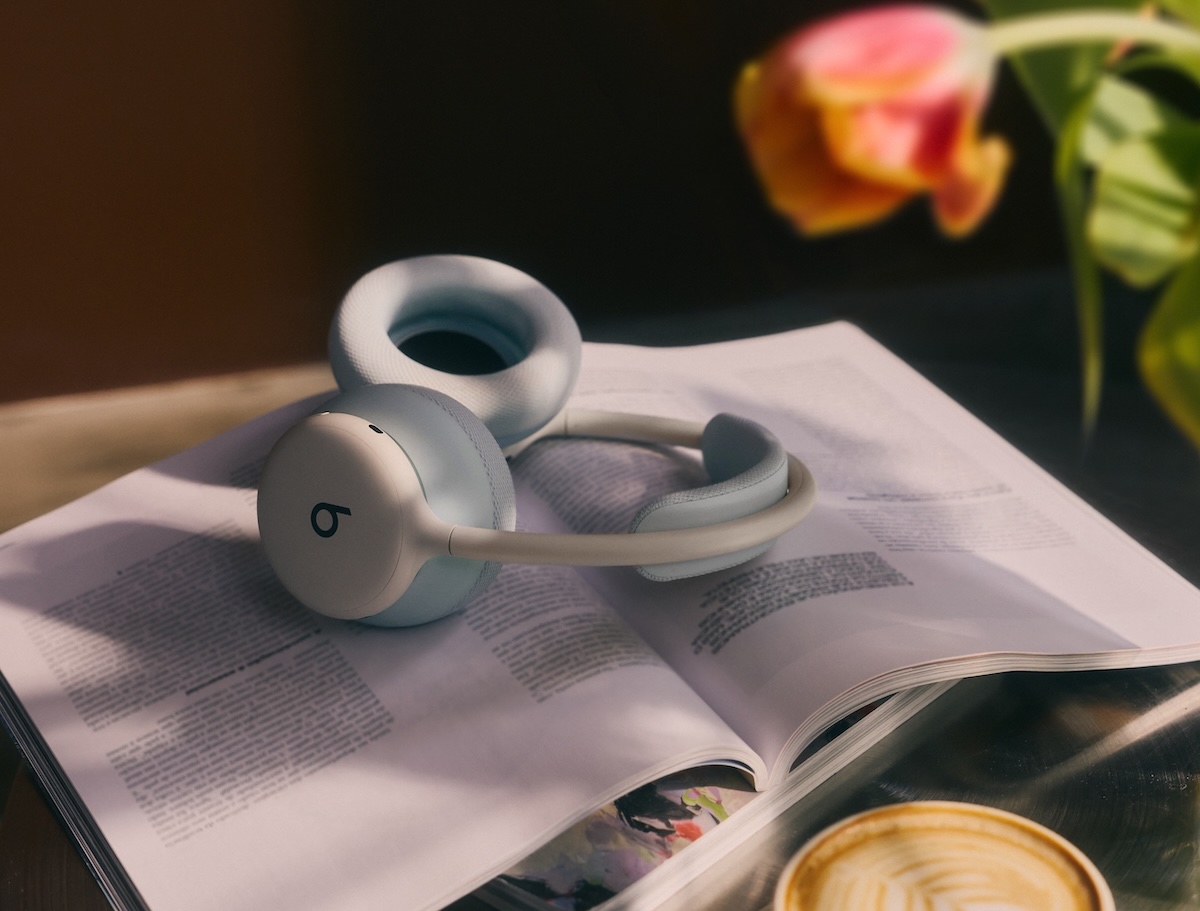 云白色 Beats 360 耳机搭配天空色耳垫，置于一本打开的书上