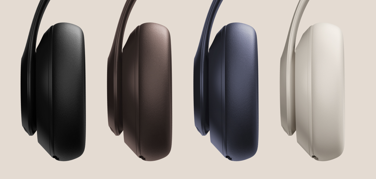 Four Beats Studio Pro headphones in black, brown, dark blue, and cream are displayed horizontally against a light background.