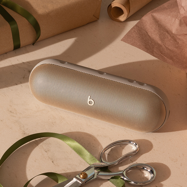 Beats Pill speaker sitting on a countertop next to a pair of scissors.