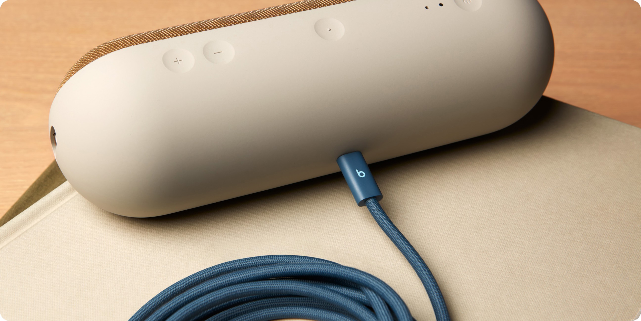 一条盘绕的 Beats 240W USB-C 转 USB-C 连接线插入电子设备，展示快速充电功能。