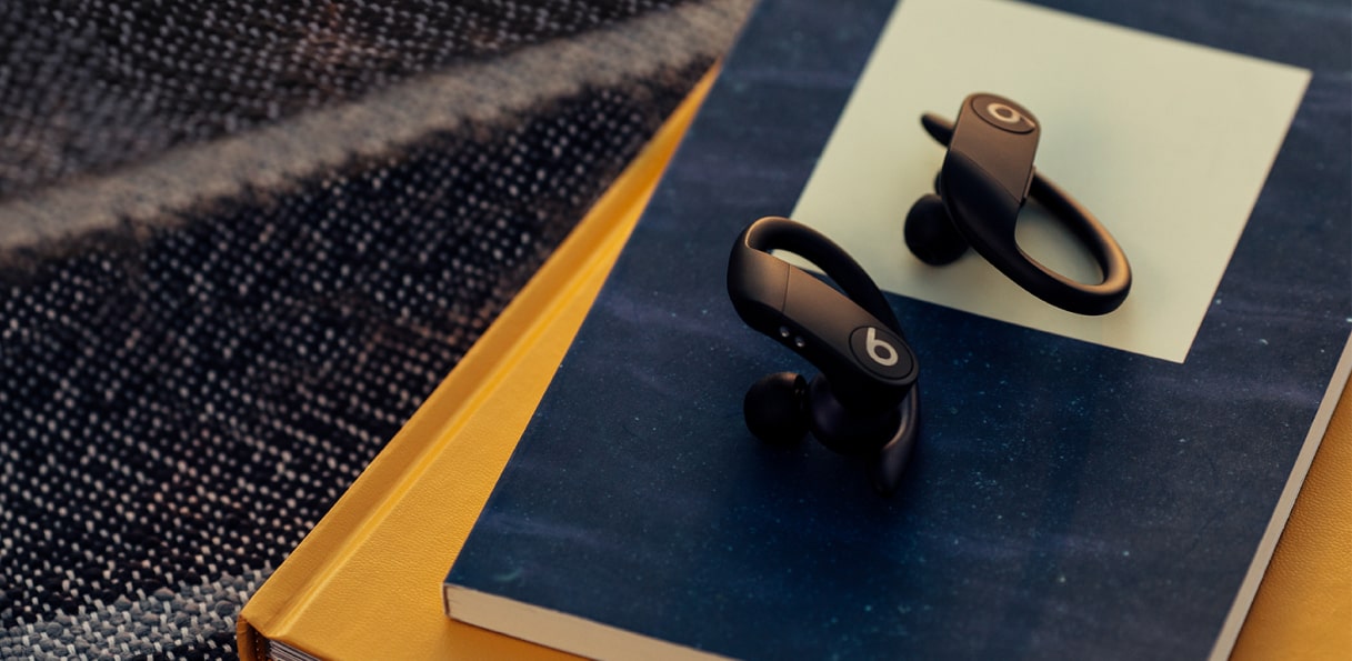 黑色 Powerbeats Pro 放在深蓝色和芥末黄色笔记本上。