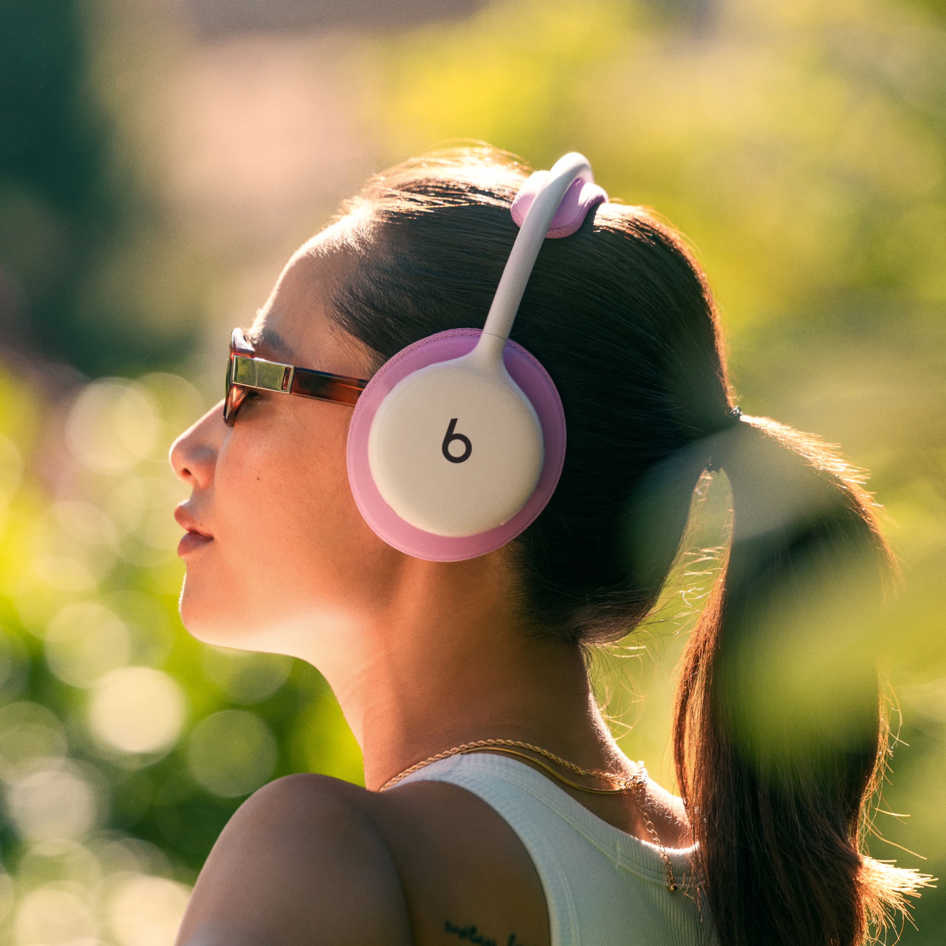 一人戴着云白色 Beats 360，耳机配有粉色机能编织头梁软垫和耳罩