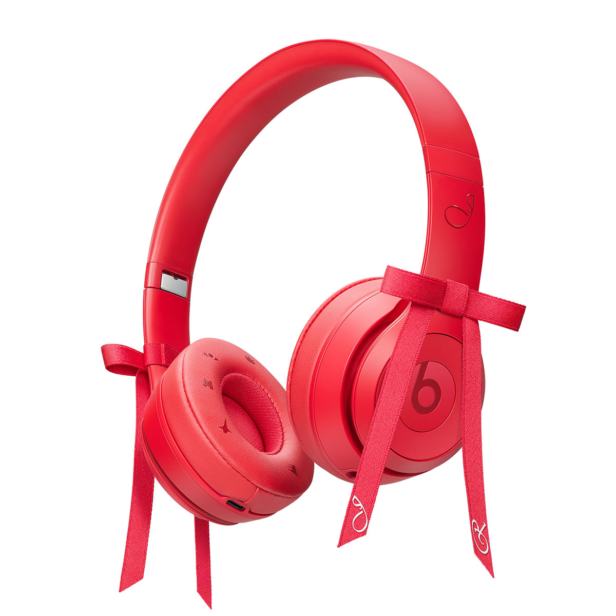 Angled right view of the Beats Solo 4 – JENNIE Special Edition headphones in Ruby Red, with two attachable red bows.