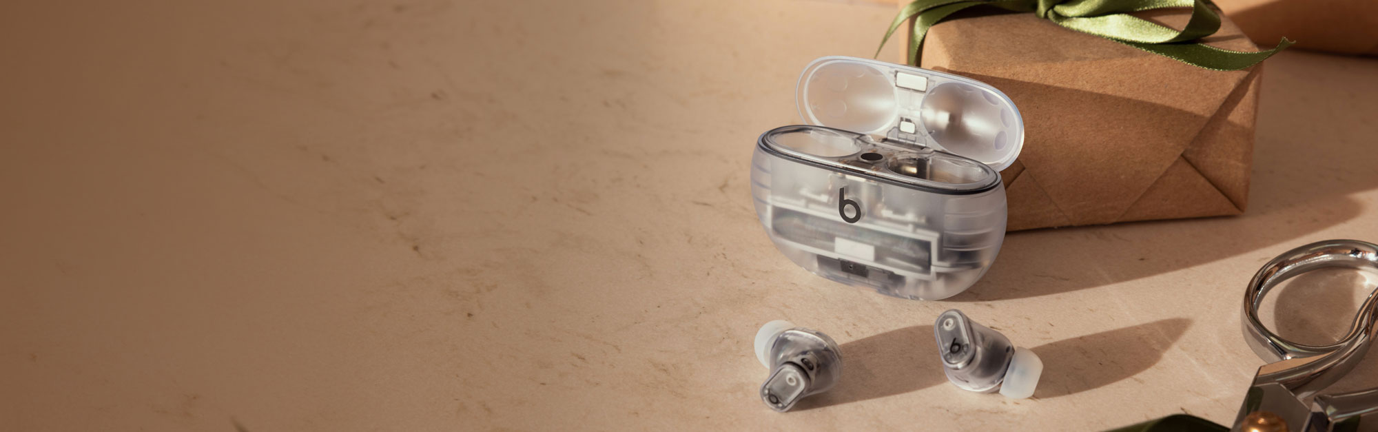 Beats Studio Buds + in Transparent infront of a gift on top of a counter.